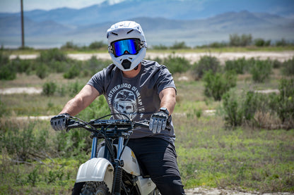 Person on a dirt bike wearing a Brotherhood of Braap shirt in the desert.